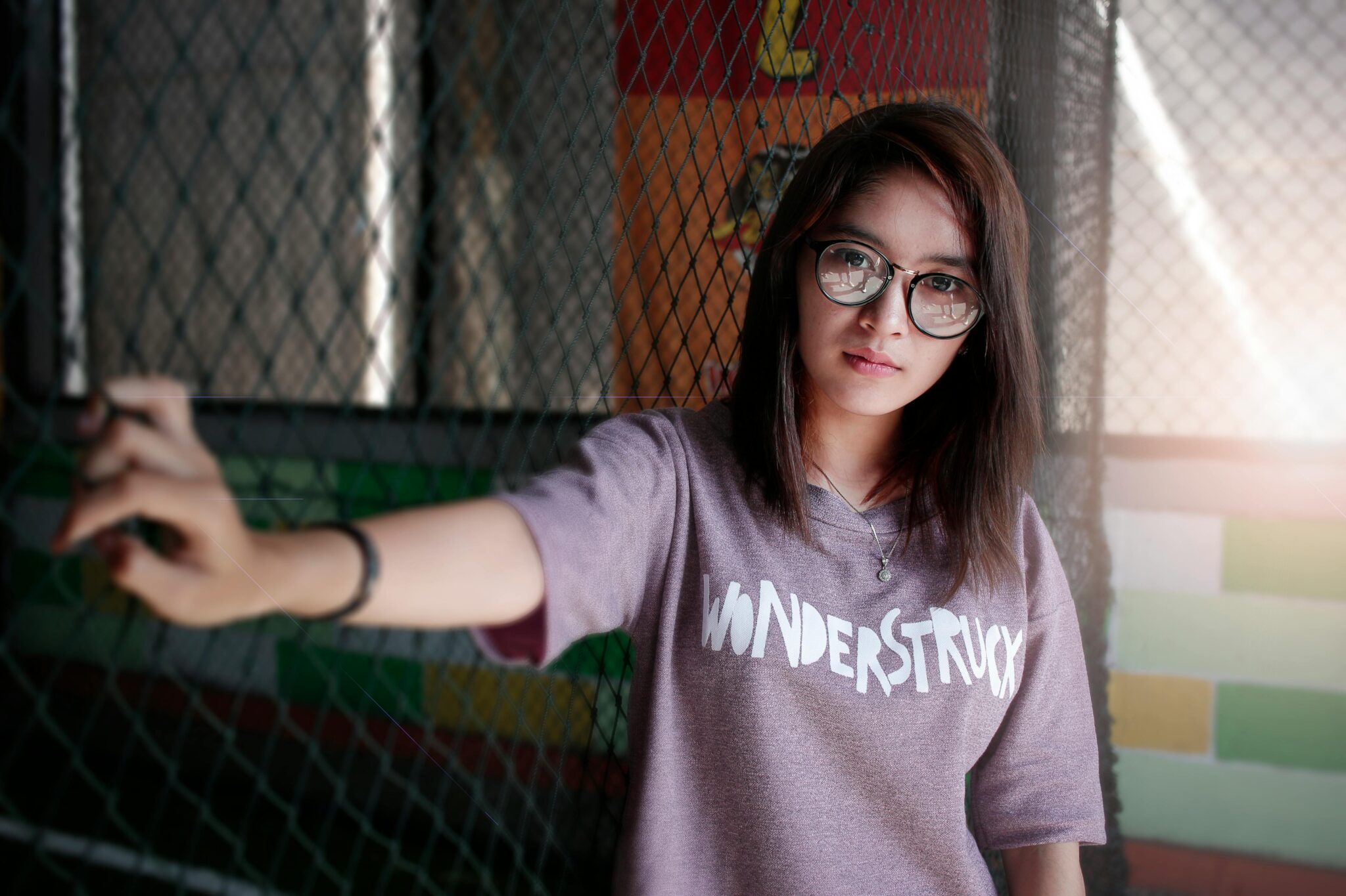 Portrait of a young woman wearing eyeglasses and a 'Wonderstruck' t-shirt posing indoors.